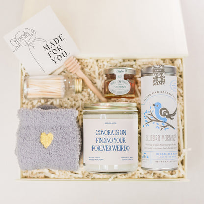 a gift box containing a candle, a jar of honey, a card and a