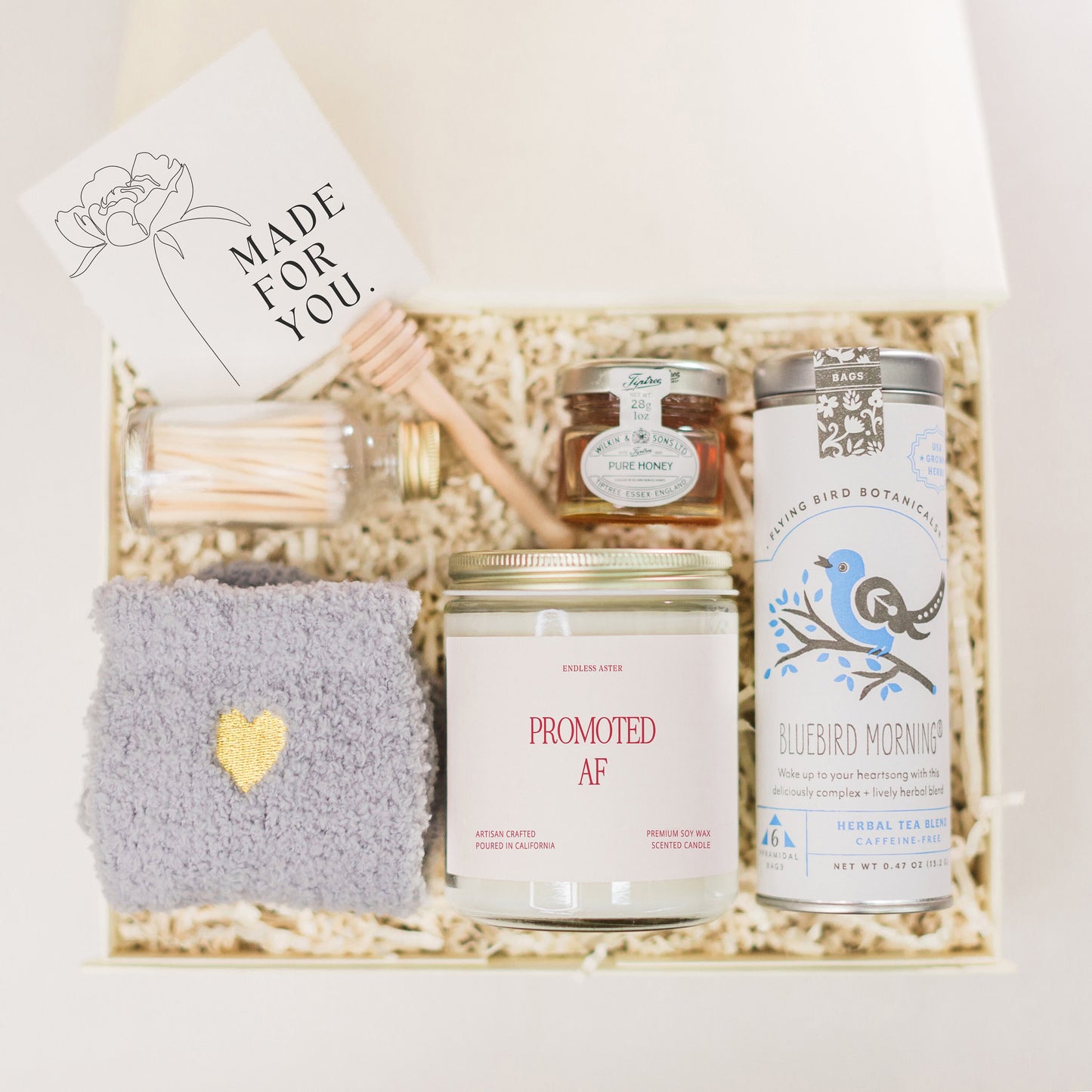 a gift box containing a candle, a candle holder, a jar of honey,