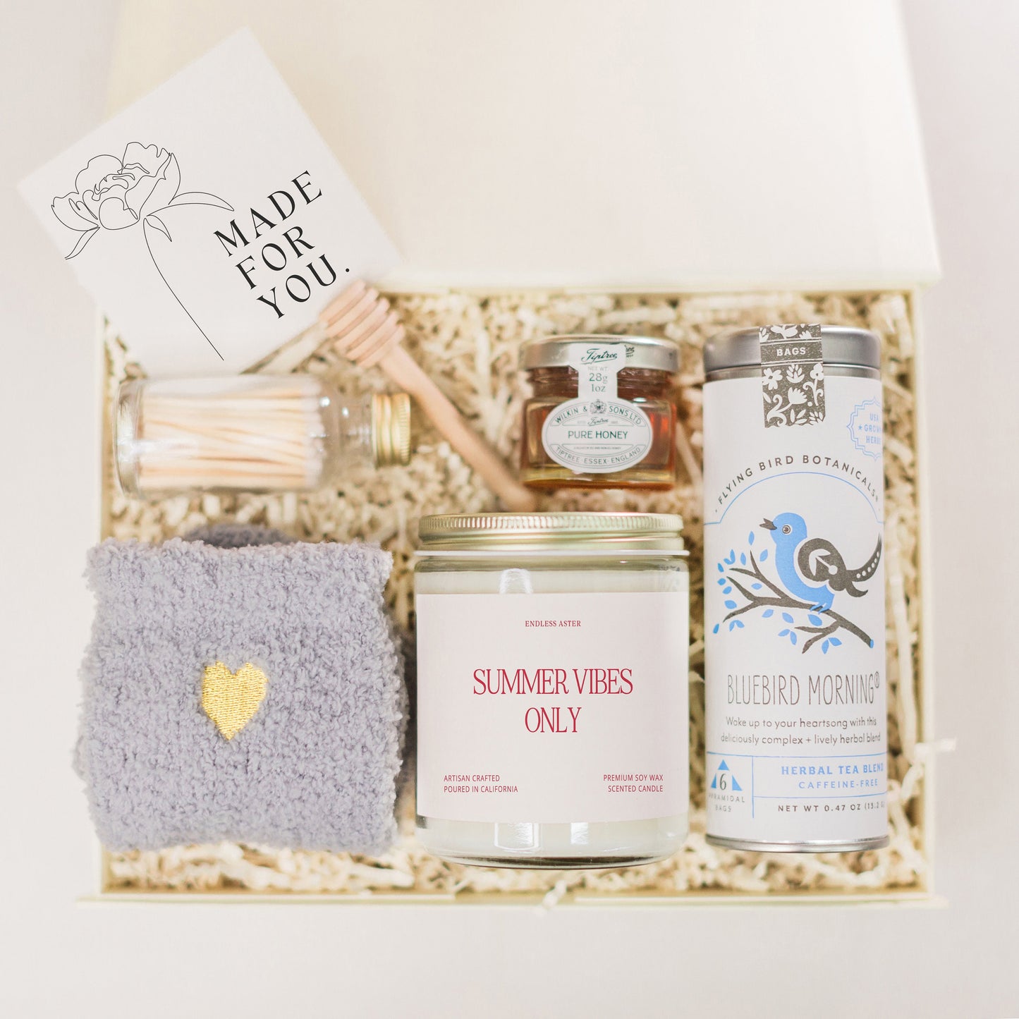 a gift box containing a candle, a candle holder, and other items