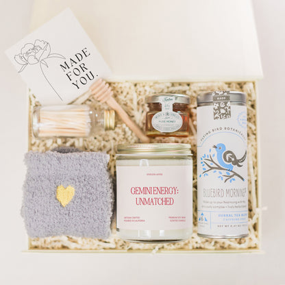 a gift box containing a candle, candle holder, and other items